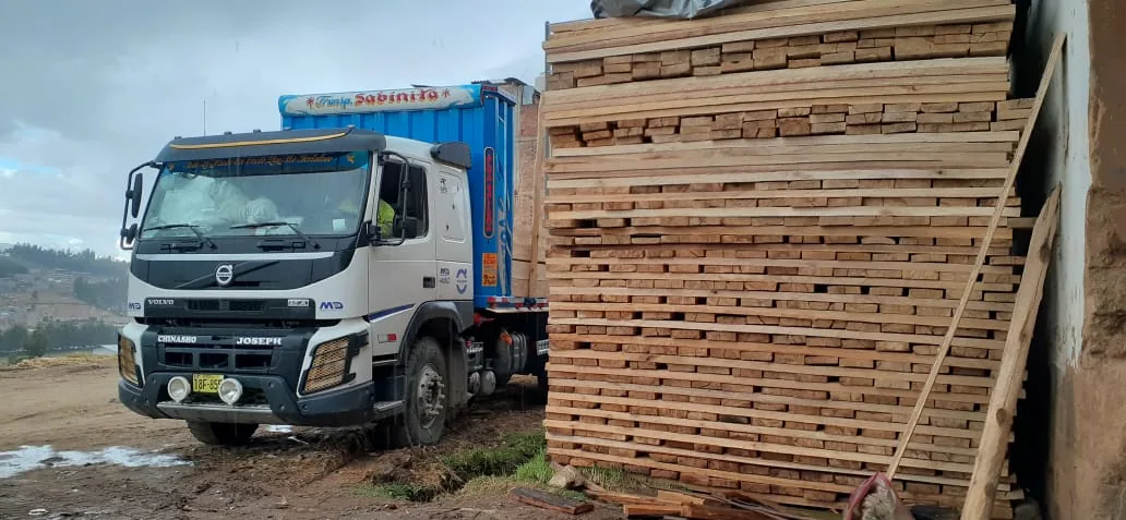 Camión Volvo de la flota junto a tablas de madera apiladas
