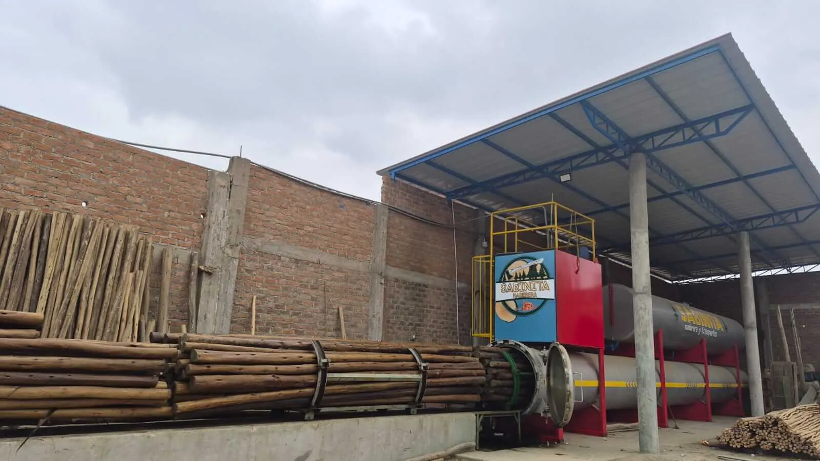 Almacén techado de Sabinita con postes apilados y maquinaria de carga
